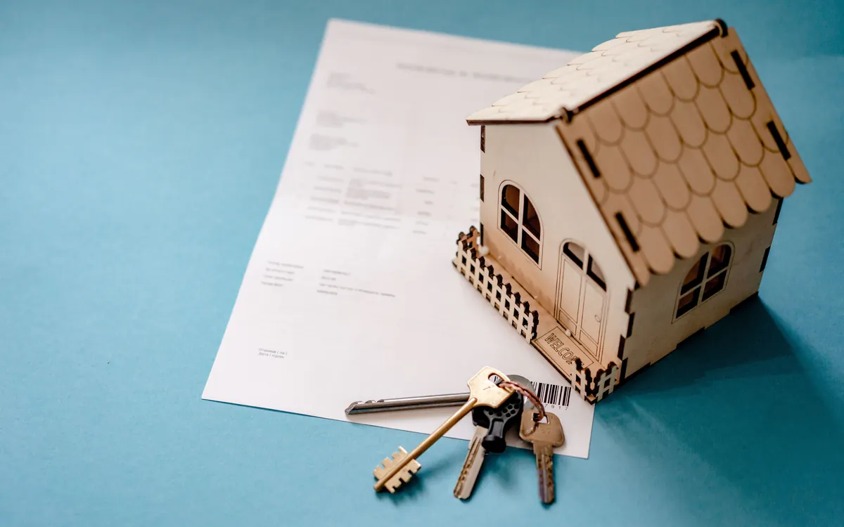Immobilienunterlagen mit Schlüssel und Hausmodell